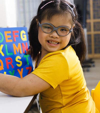 Asian girl with Down's syndrome play alphabet puzzle toy.